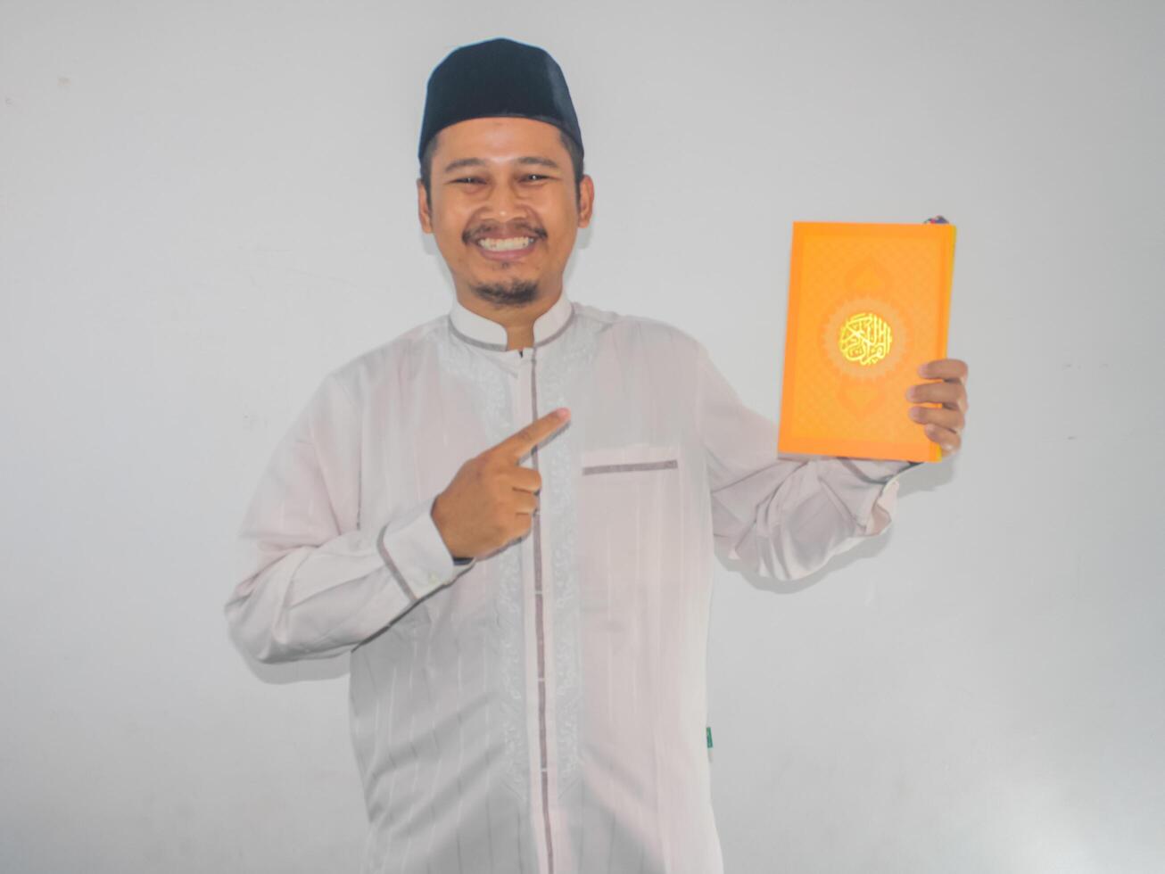 Moslem asiatisch Mann lächelnd während zeigen zu ein Buch Das er halt foto