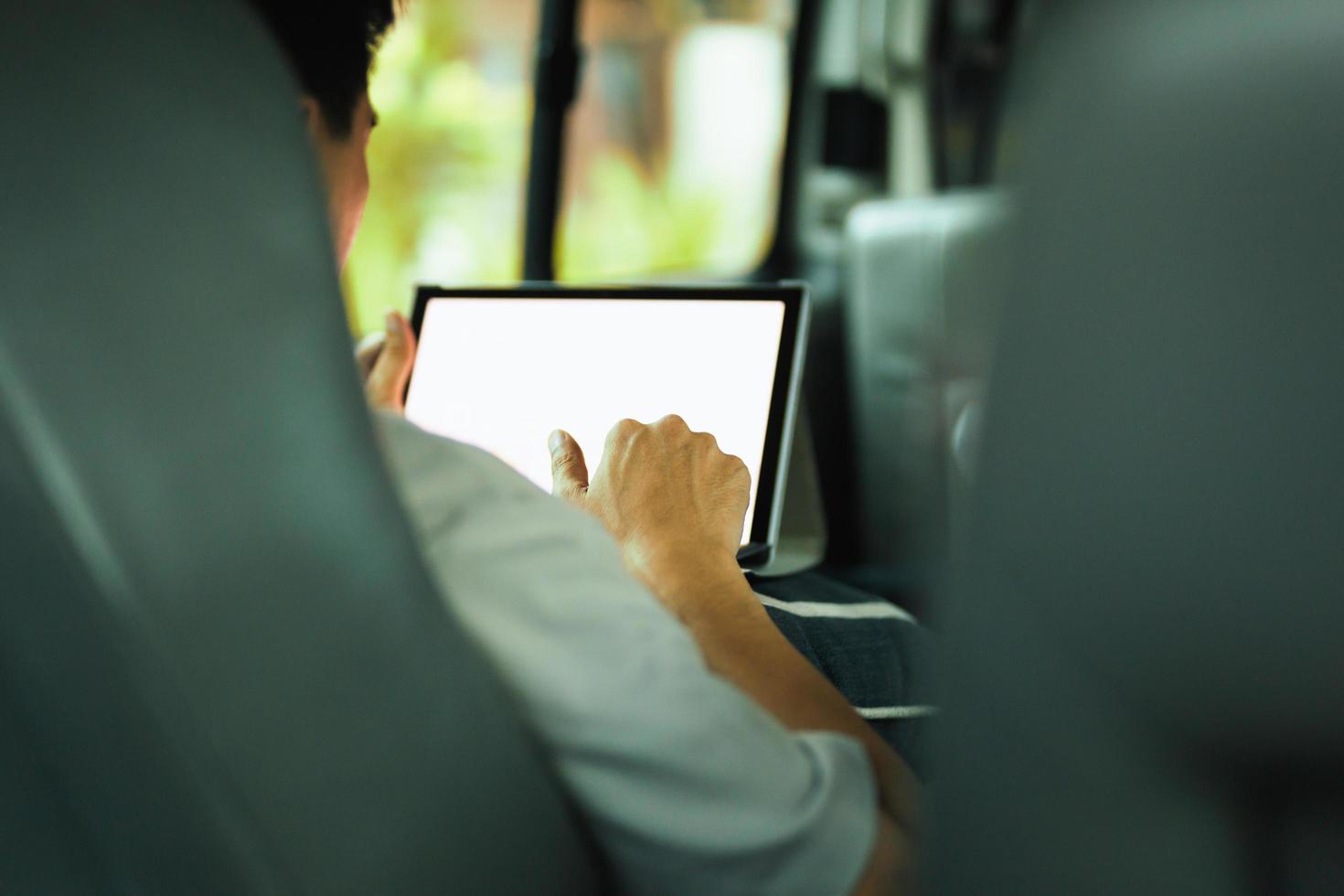 Geschäftsmann, der am Laptop auf dem Rücksitz des modernen Autos arbeitet. foto