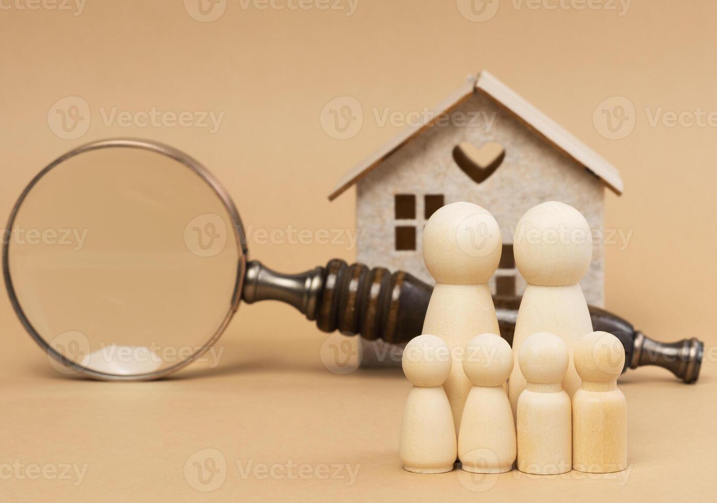 Vergrößerung Glas und ein Familie von hölzern zahlen auf das Hintergrund von ein Haus, das Konzept von suchen zum echt Nachlass Vermietung foto