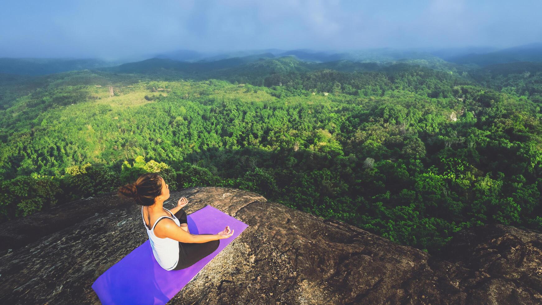 asiatische frauen entspannen sich im urlaub. spielen, wenn Yoga. auf der Bergfelsenklippe. Natur der Bergwälder in Thailand foto