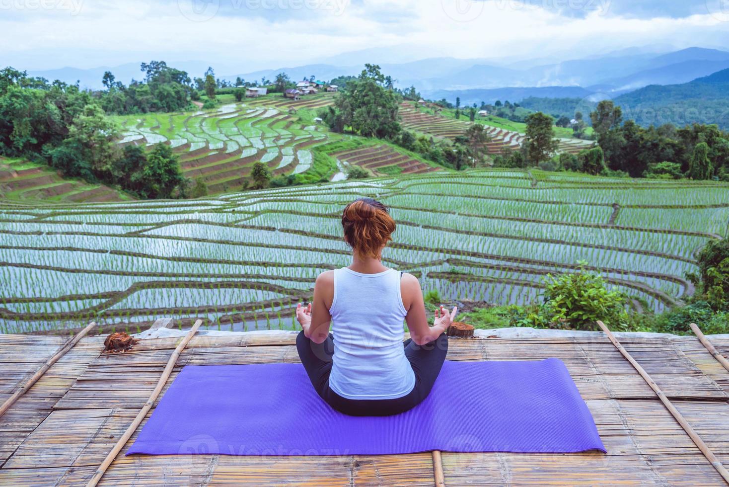 asiatische frau entspannen sich im urlaub. spielen, wenn Yoga. auf der balkonlandschaft naturfeld foto
