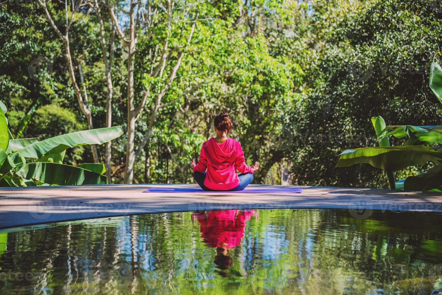 junge frau reisen natur sie steht übung am pool entspannend, reflexionen der asiatischen frau auf der wasseroberfläche. foto