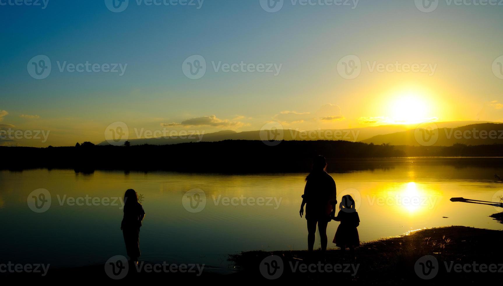 Silhouetten von Mutter und Kind stehen bei Sonnenuntergang auf dem See, Stausee Amphoe Wang Saphung Loei thailand foto