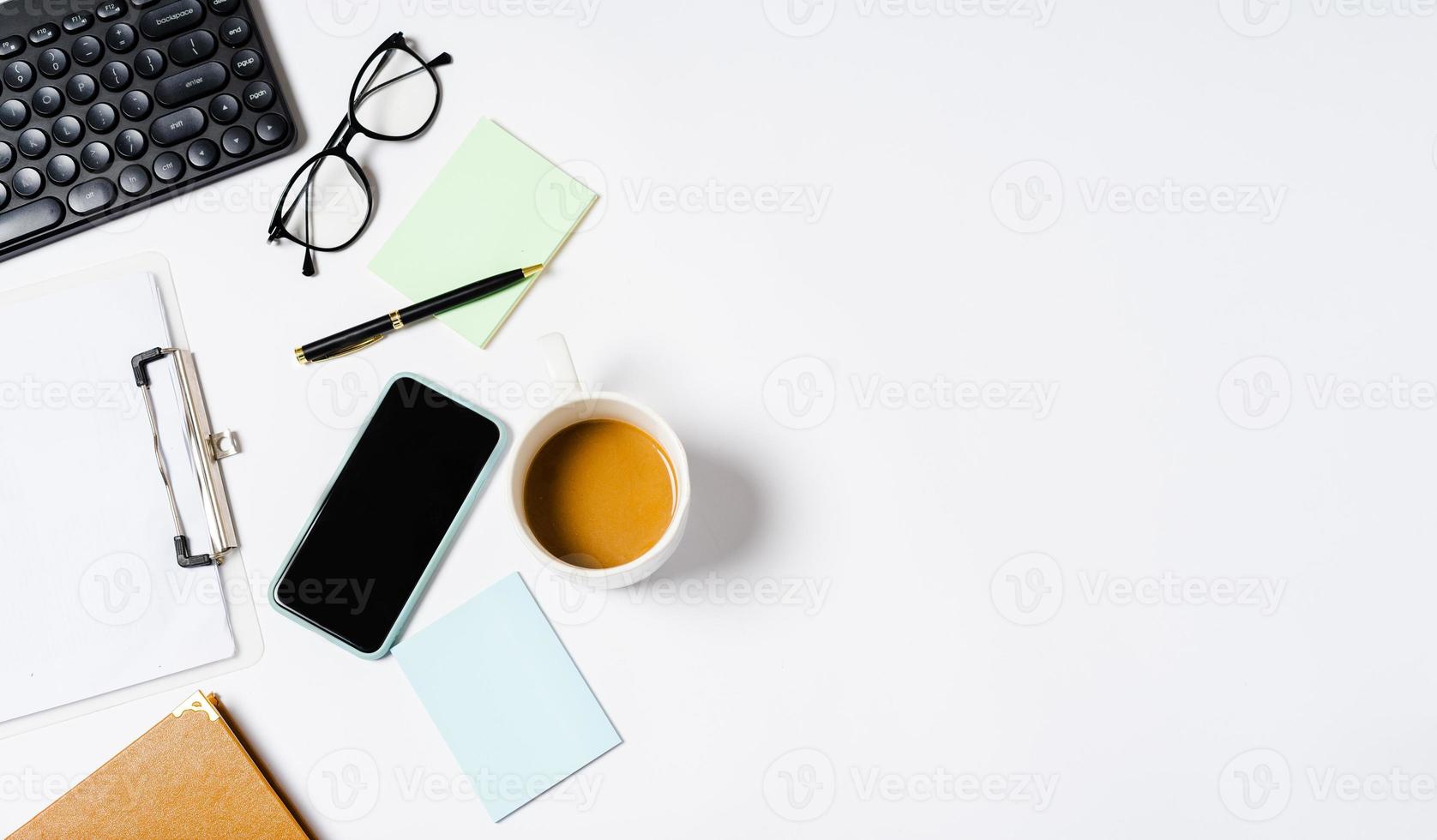 Draufsicht auf Kaffee, Buch, Notizbuch, Stift, Tastatur, Telefon auf weißem Hintergrund foto