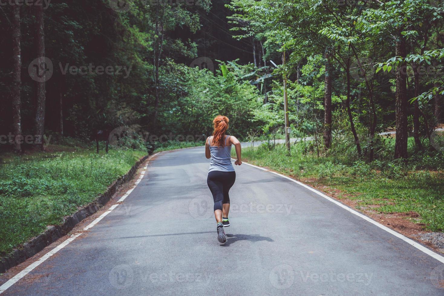 Frauen trainieren auf der Straße. Naturpark. Mädchen, das Beine anhebt, um zu trainieren. Übung, Laufen, Mädchen, das Joggen läuft. foto