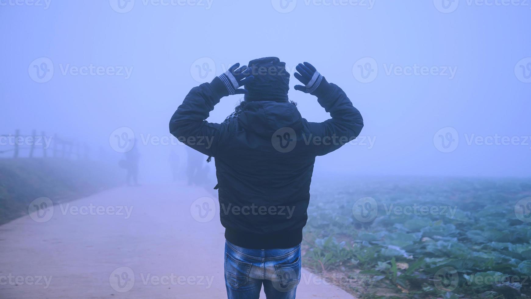 asiatischer Mann entspannt sich im Urlaub. gerne in den Urlaub reisen. im nebligen Winter foto