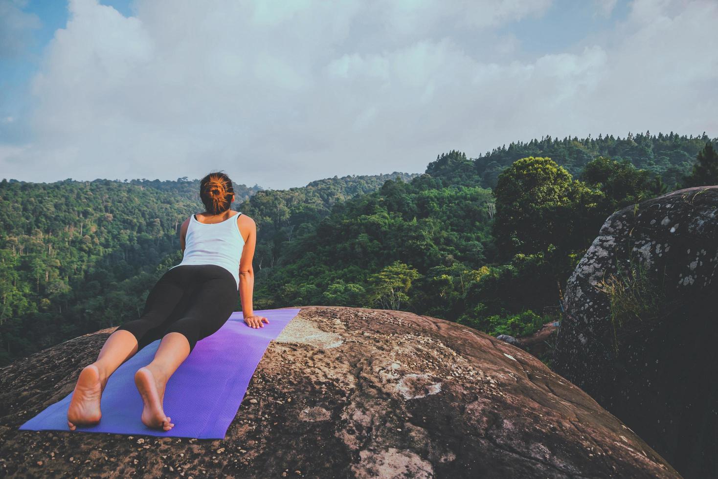 asiatische frauen entspannen sich im urlaub. spielen, wenn Yoga. auf der Bergfelsenklippe. Natur der Bergwälder in Thailand foto