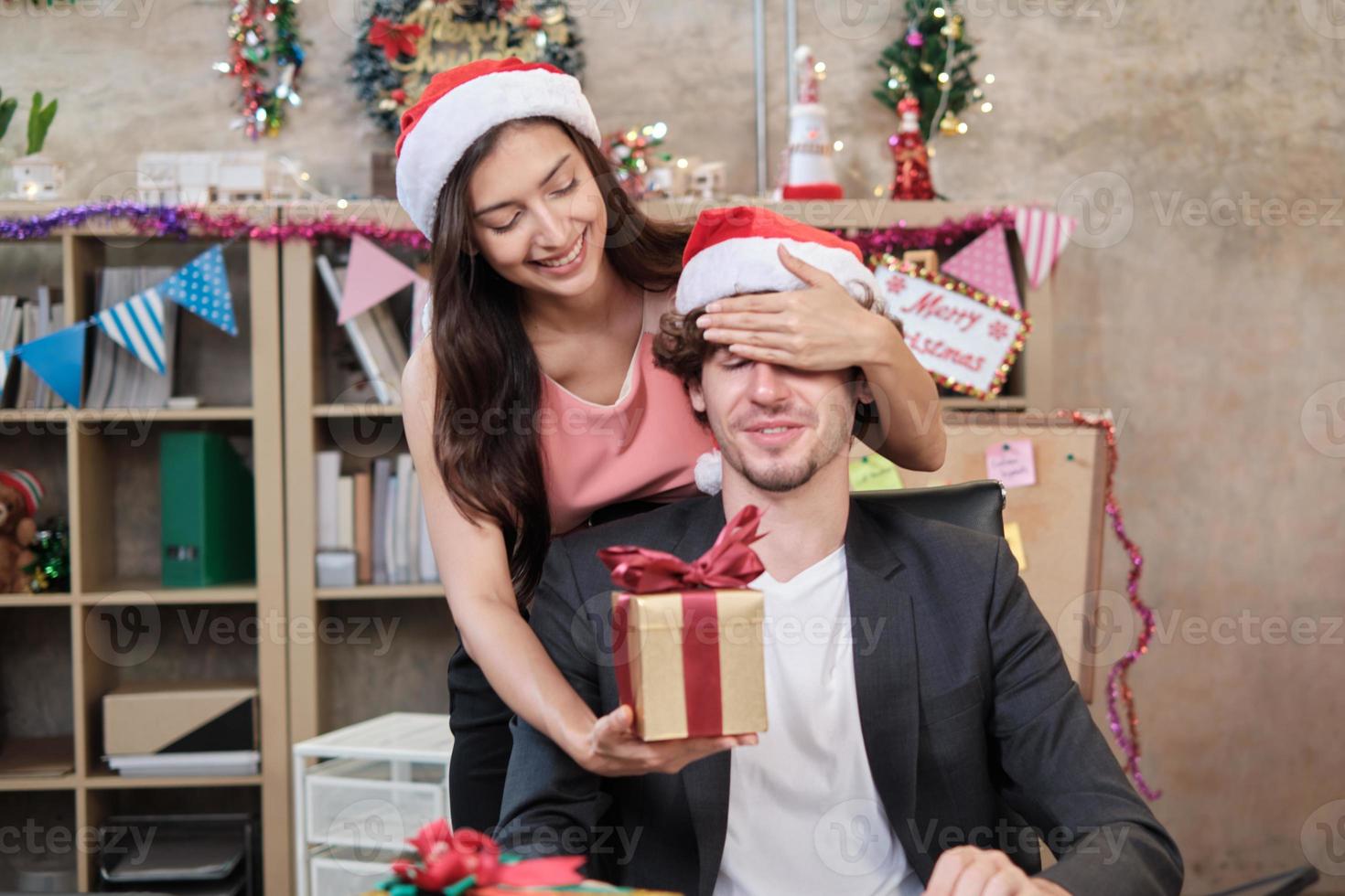 Überraschen Sie das Team und den Chef von zwei Mitarbeitern, indem Sie Geschenke geben, während Sie vor dem Betriebsurlaub am Büroarbeitsplatz arbeiten, ist für die Weihnachtsfeier und die Neujahrsfeier dekoriert. foto