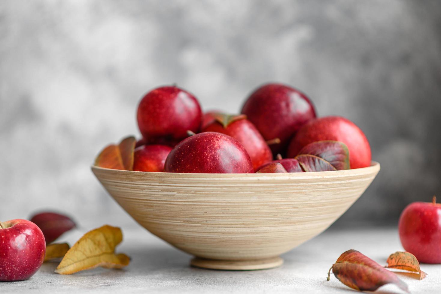 schöne frische rote Äpfel mit Herbstlaub in einer Holzvase foto