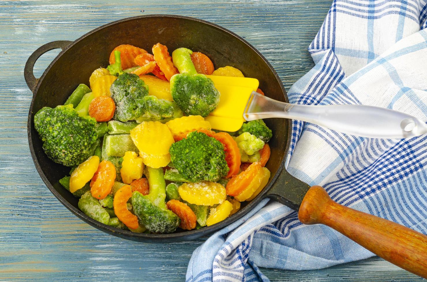 vegetarisches Essen. Mischung aus gefrorenem Frischgemüse zum Braten auf blauem Holzhintergrund. Studiofoto foto