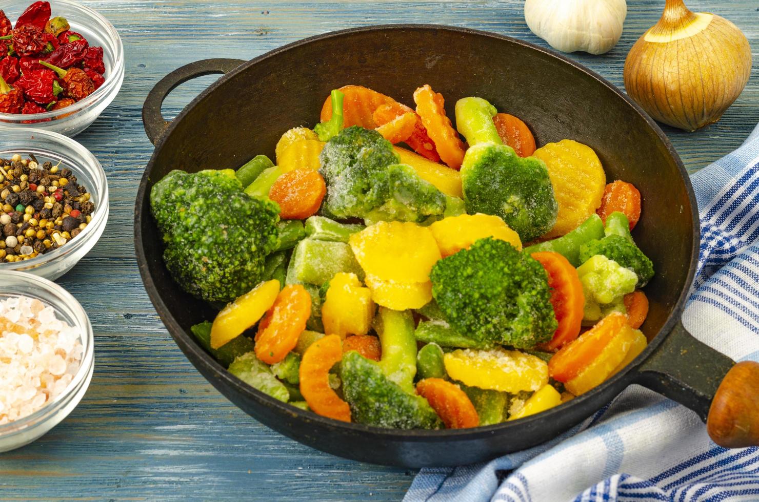 vegetarisches Essen. Mischung aus gefrorenem Frischgemüse zum Braten auf blauem Holzhintergrund. Studiofoto foto