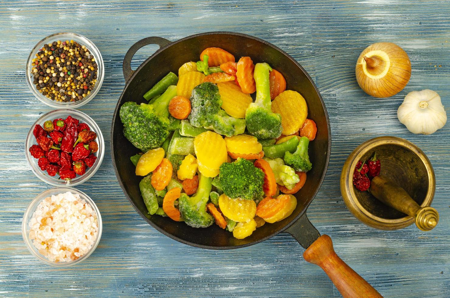 vegetarisches Essen. Mischung aus gefrorenem Frischgemüse zum Braten auf blauem Holzhintergrund. Studiofoto foto