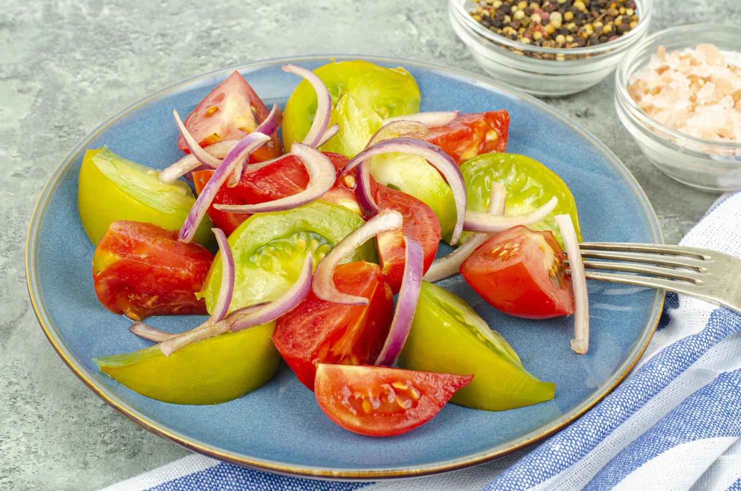 Diätessen. Salat aus Scheiben von frischen hellen Tomaten und Zwiebeln. Studiofoto foto