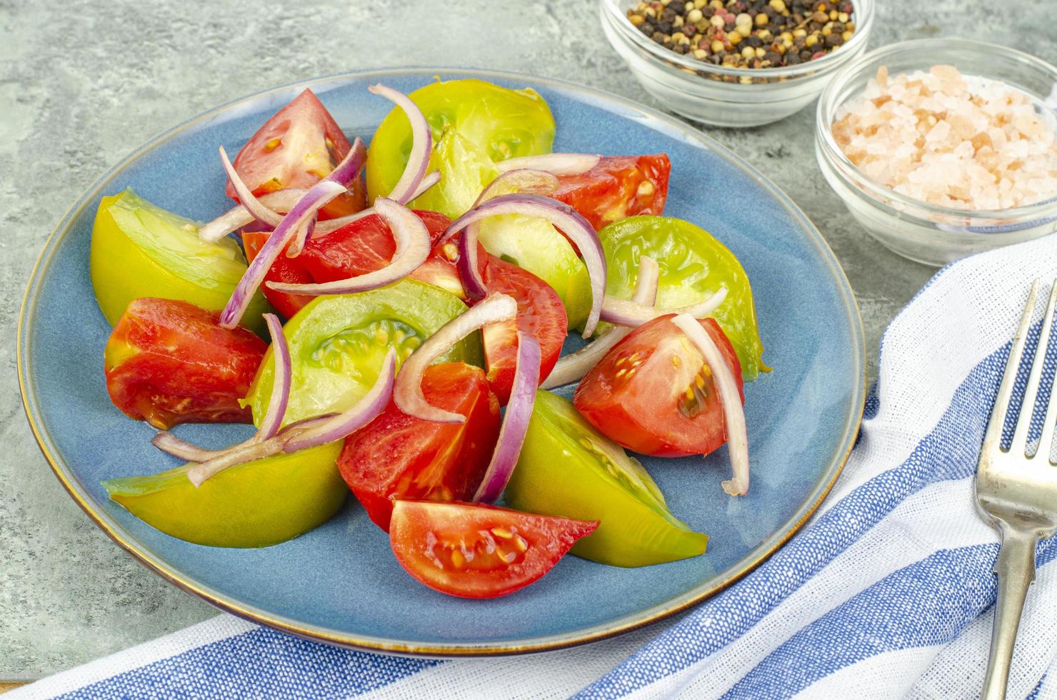 Diätessen. Salat aus Scheiben von frischen hellen Tomaten und Zwiebeln. Studiofoto foto