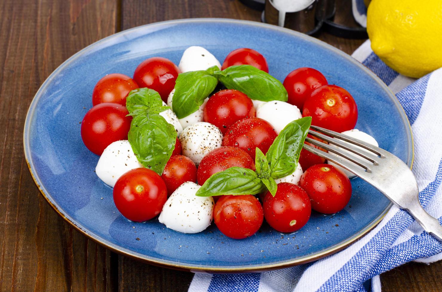 köstlicher italienischer Caprese-Salat mit Basilikum, Mozzarella und Kirschtomaten. Studiofoto. foto
