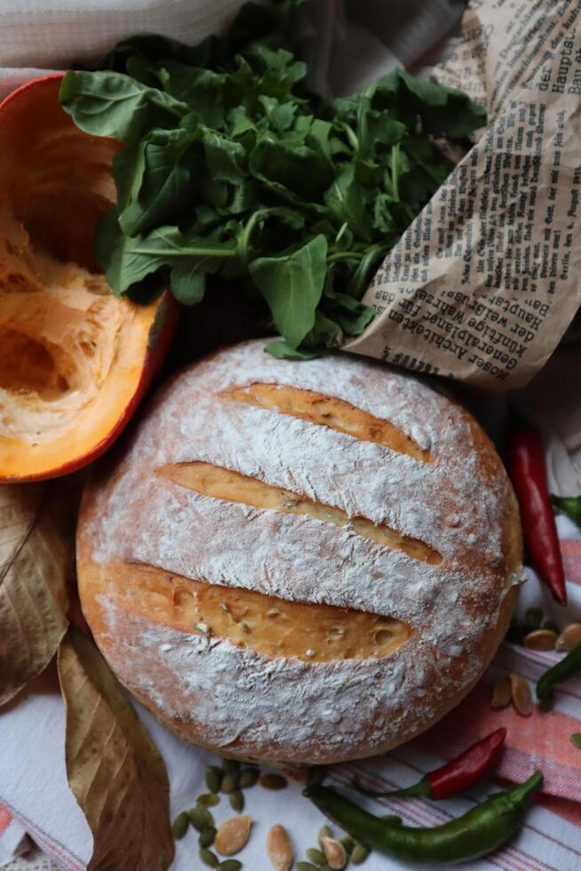 hausgemacht Sauerteig Brot frisch gebacken mit Gemüse und Grüns Dekoration foto