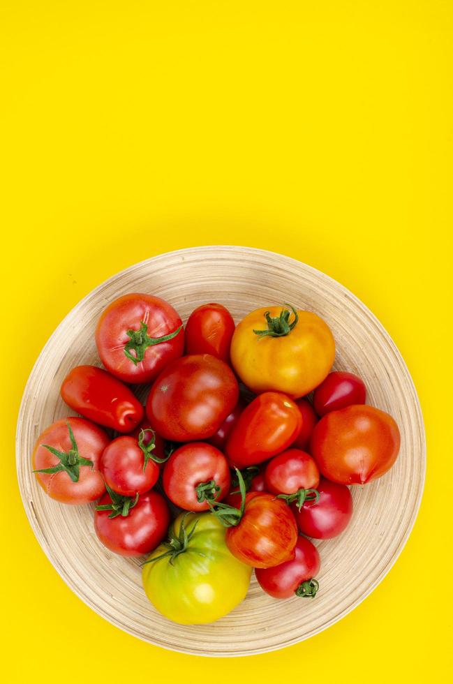 Mischung aus reifen bunten Tomaten auf leuchtend gelbem Hintergrund. Studiofoto foto
