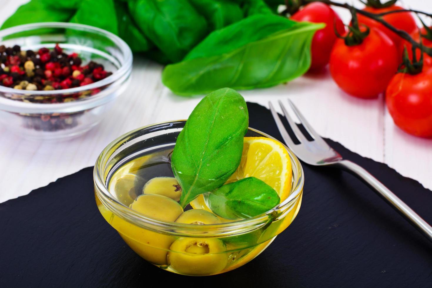 grüne Oliven mit Öl und Basilikum foto