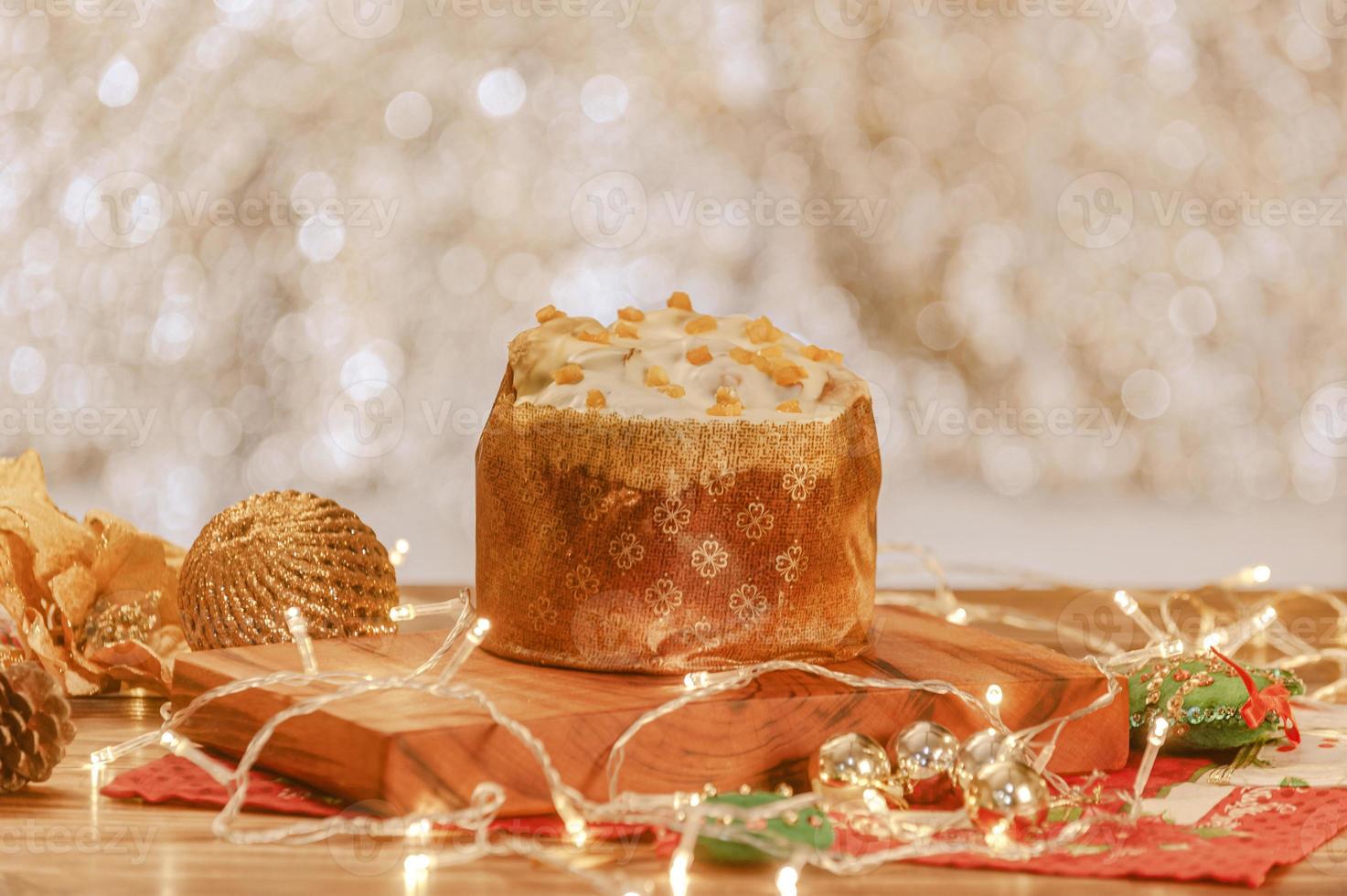 Panettone aus weißer Schokolade mit getrockneten Aprikosen auf Holztisch mit Weihnachtsschmuck foto