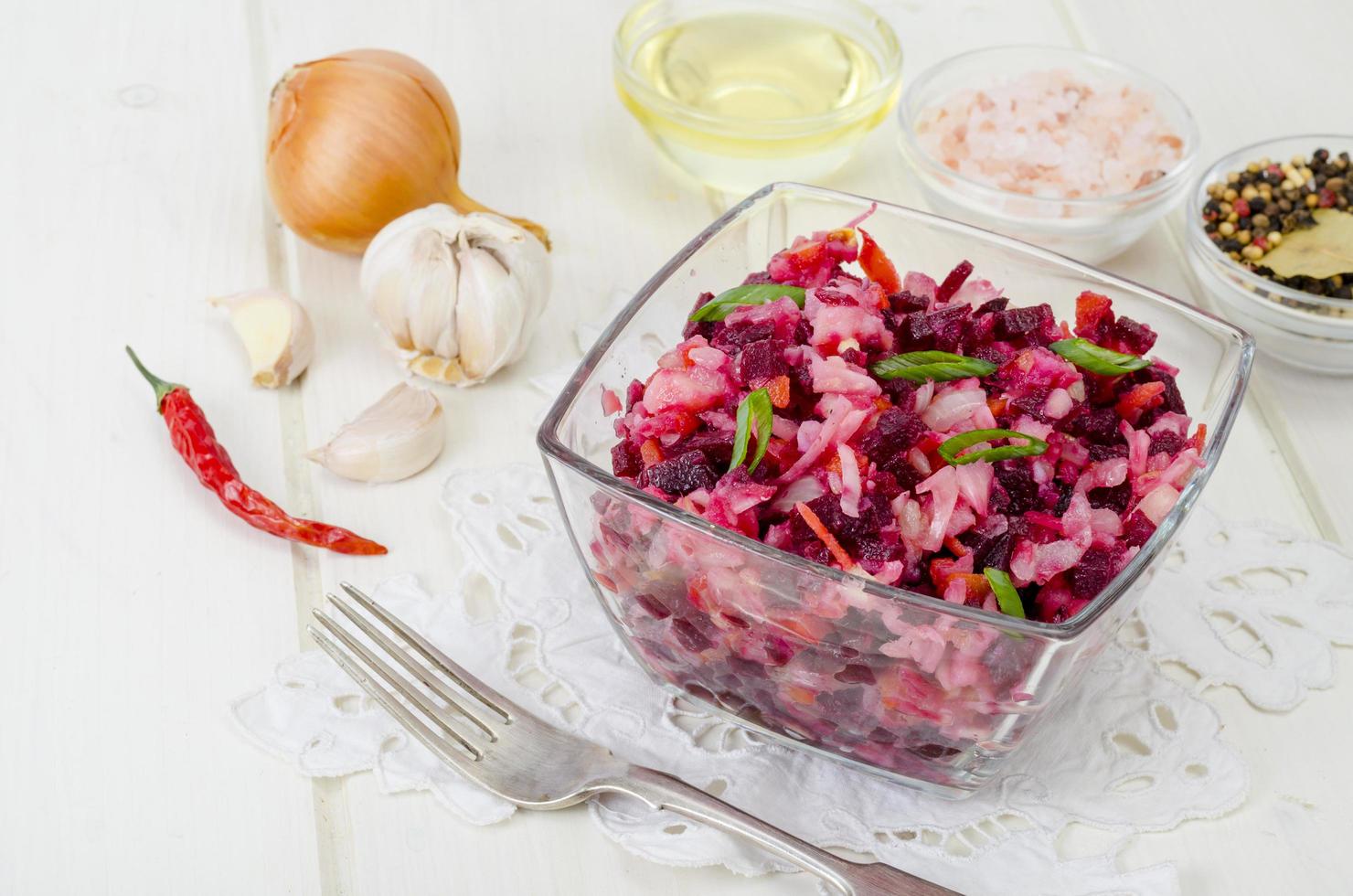 Gemüsesalat mit Rüben, Gewürzen, Zwiebeln, Knoblauch auf Holztisch foto