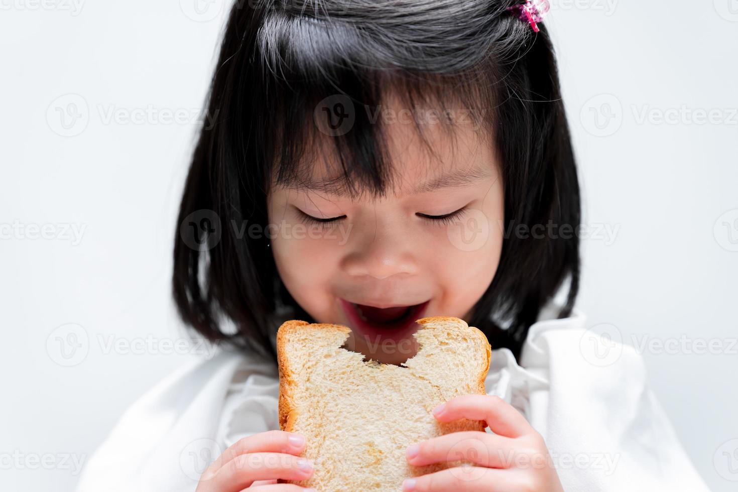 Porträt kleines Mädchen, das Weißbrot isst. auf weißem Hintergrund. foto