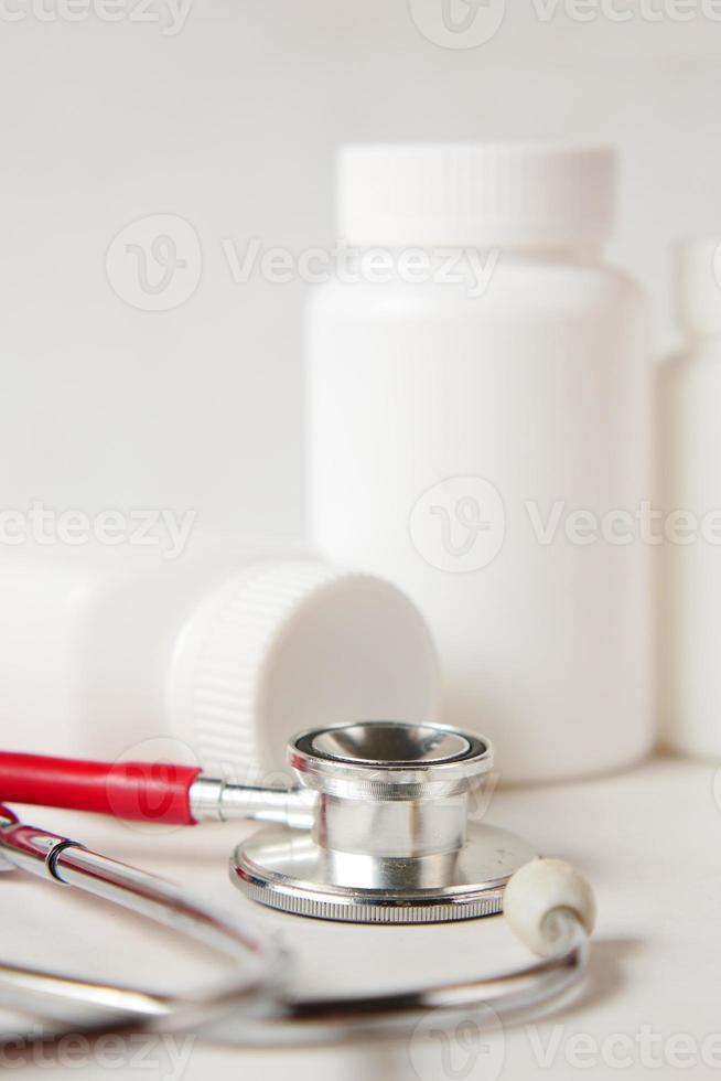 Behälter für medizinische Tabletten und Stethoskop auf weißem Hintergrund foto