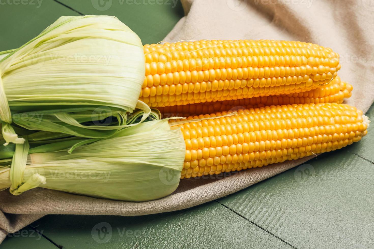 frische Maiskolben auf farbigem Holzhintergrund foto