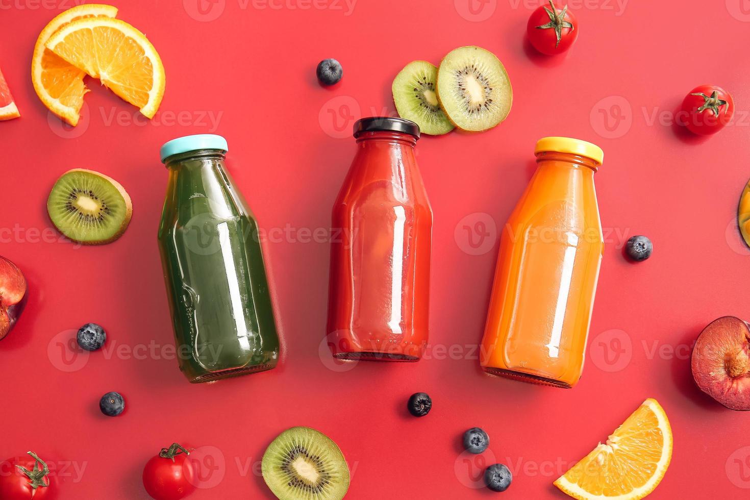 Flaschen mit gesundem Saft, Obst und Gemüse auf farbigem Hintergrund foto