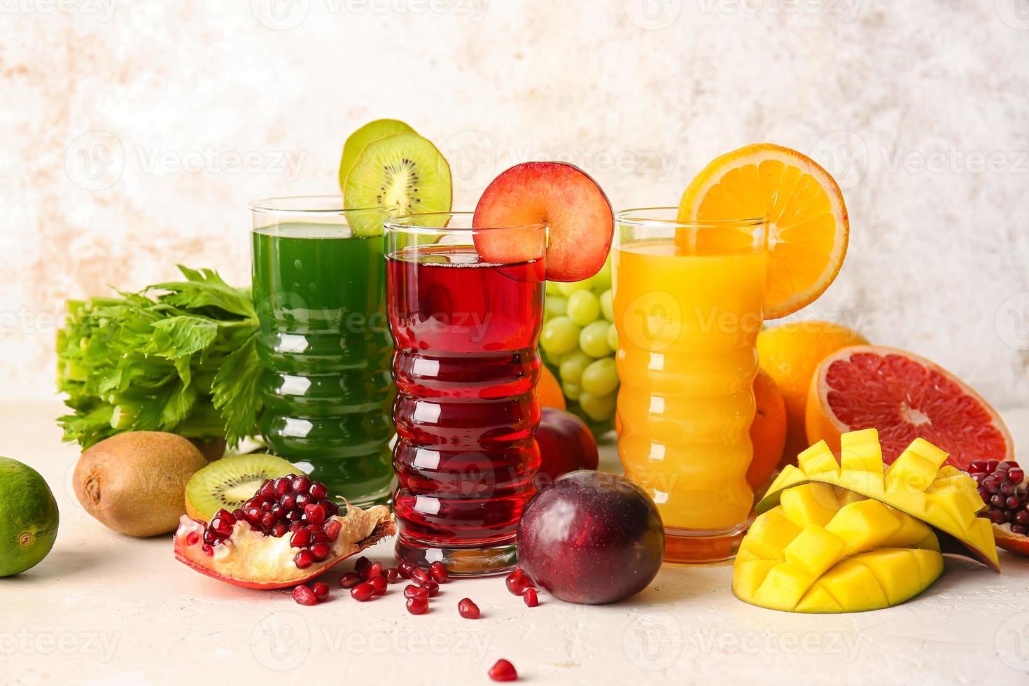 Gläser mit gesundem Saft, Obst und Gemüse auf hellem Hintergrund foto