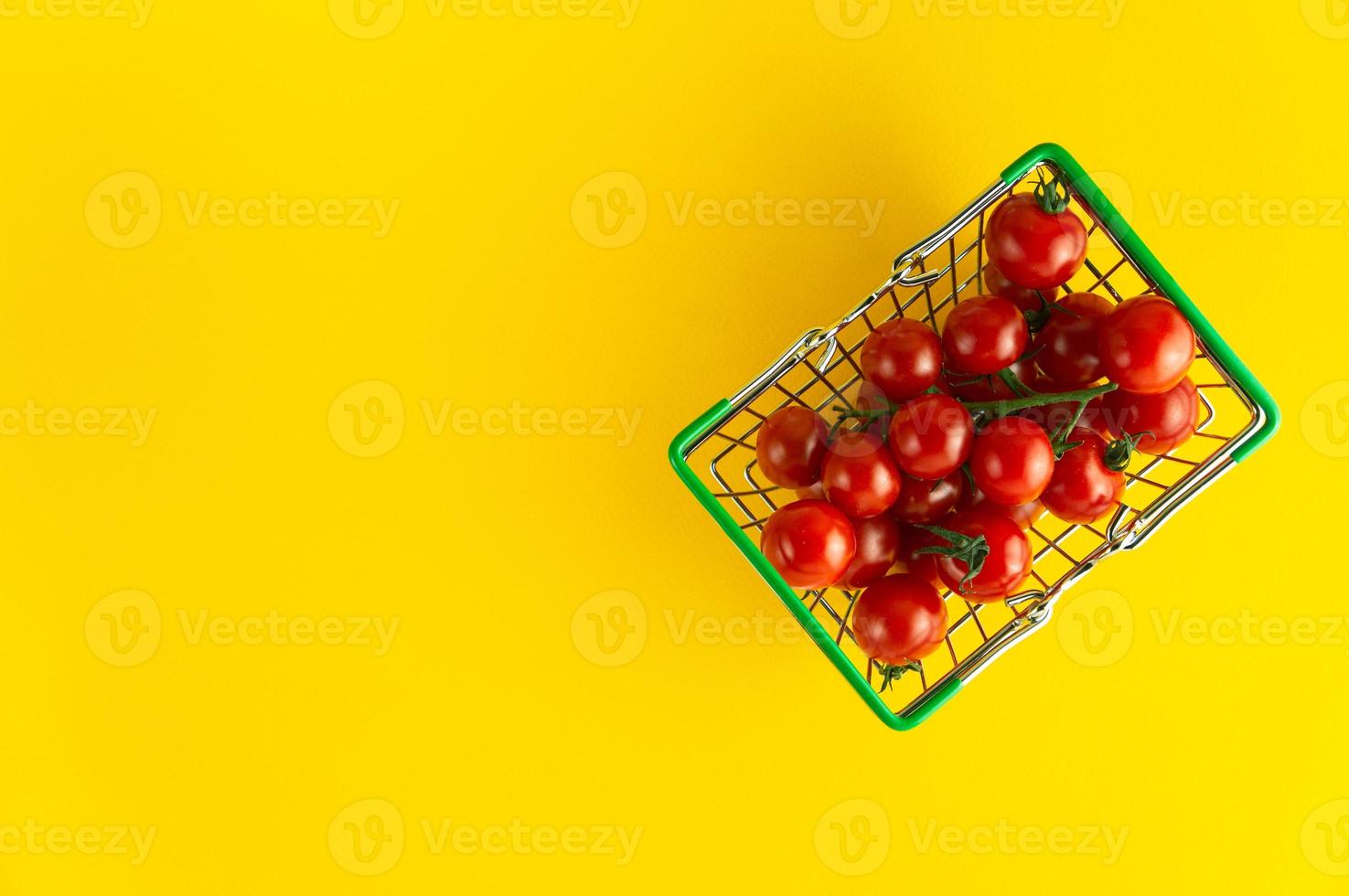 Kirschtomaten in einem Korb auf hellgelbem Hintergrund mit einem leeren Platz für eine Inschrift. foto