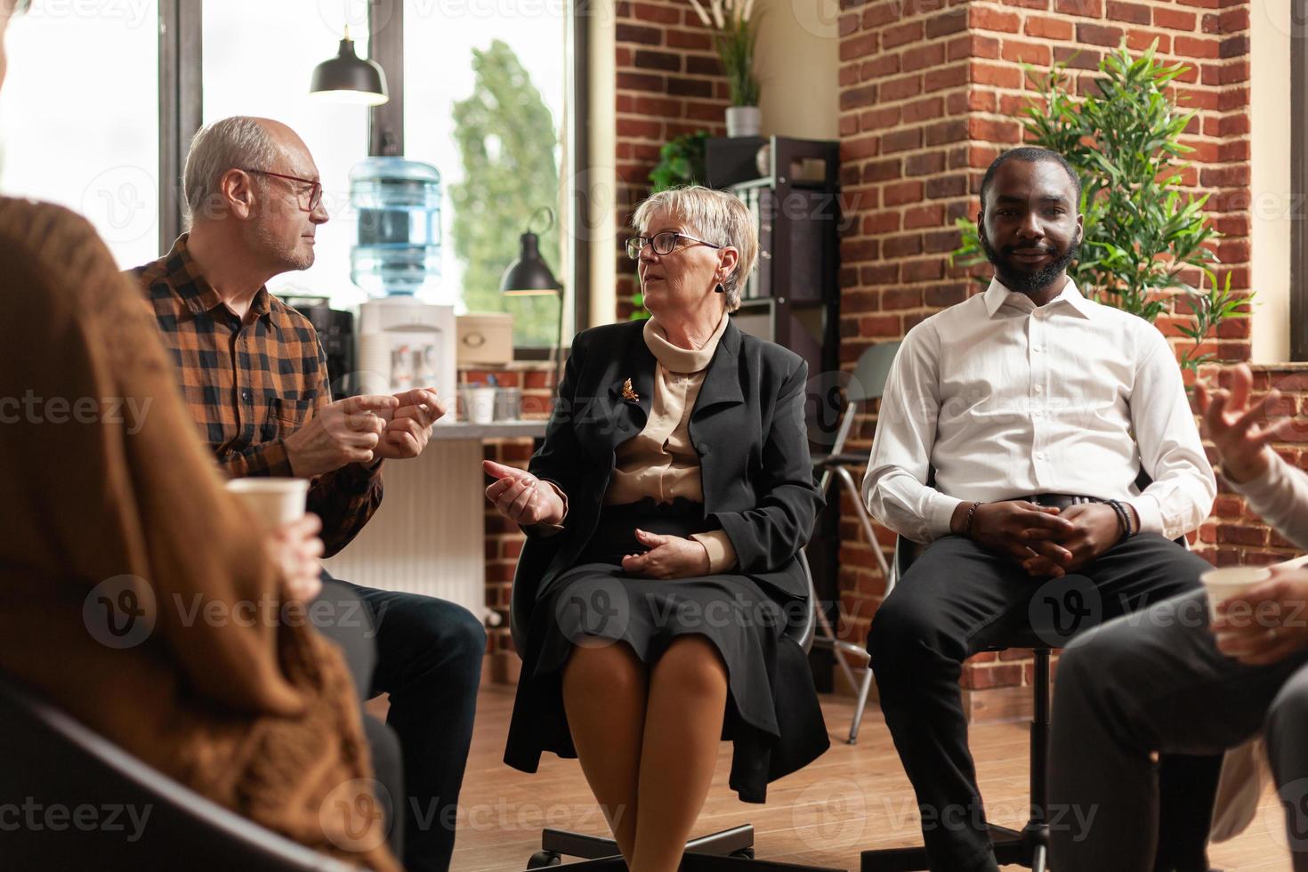 Psychiaterin, die Unterstützungsgespräche mit Leuten bei einem Gruppentreffen führt foto