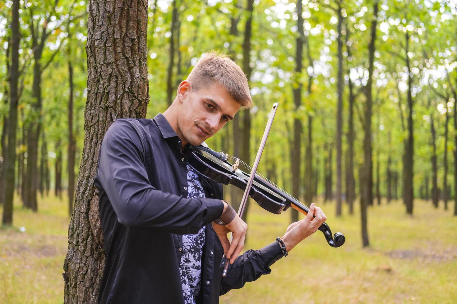 junges Männchen spielt auf der Geige im Sommerpark foto