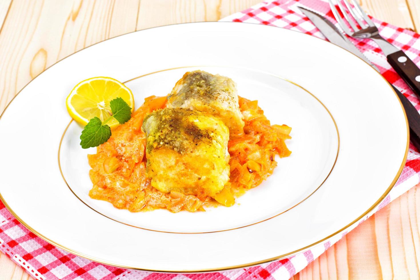 Fisch auf Griechisch mit Zwiebeln und Karotten foto