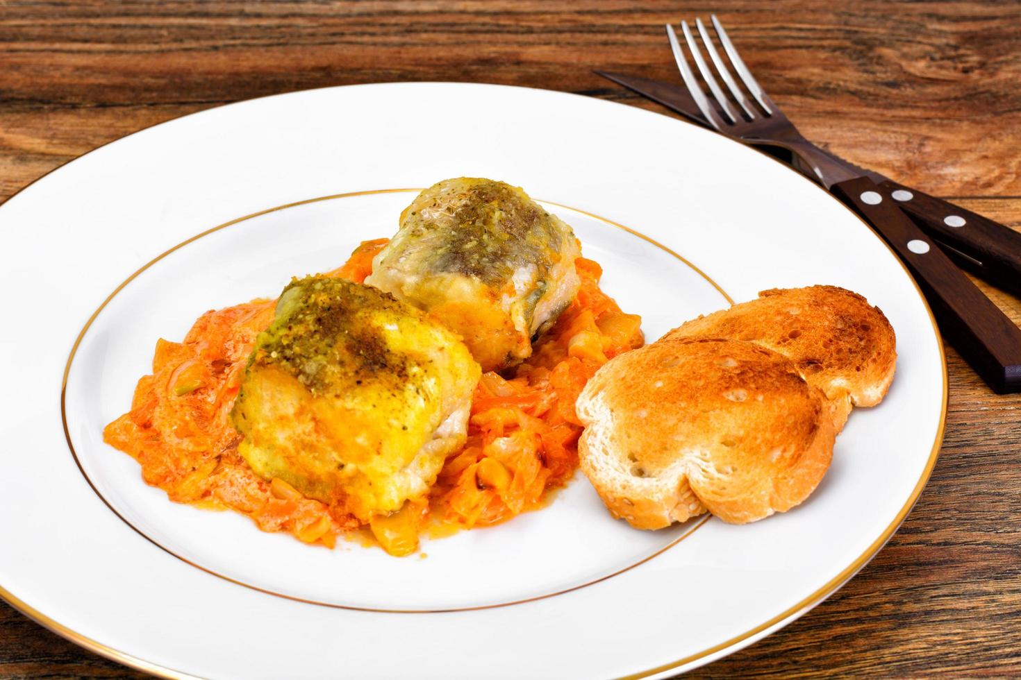 Fisch auf Griechisch mit Zwiebeln und Karotten foto