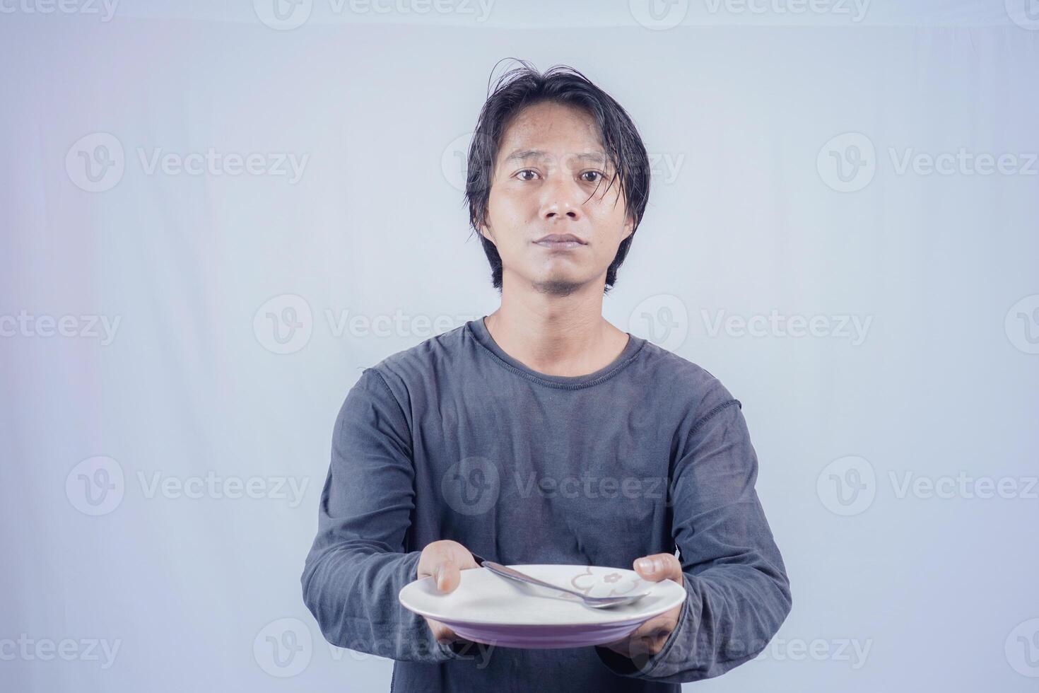 Porträt von asiatisch Männer Wer sind hungrig halten leeren Platten zu Fragen zu Essen mit ein Weiß Hintergrund Das ist isoliert zum das Fotokopie Raum auf Es. Speisekarte Dichter Konzept. foto