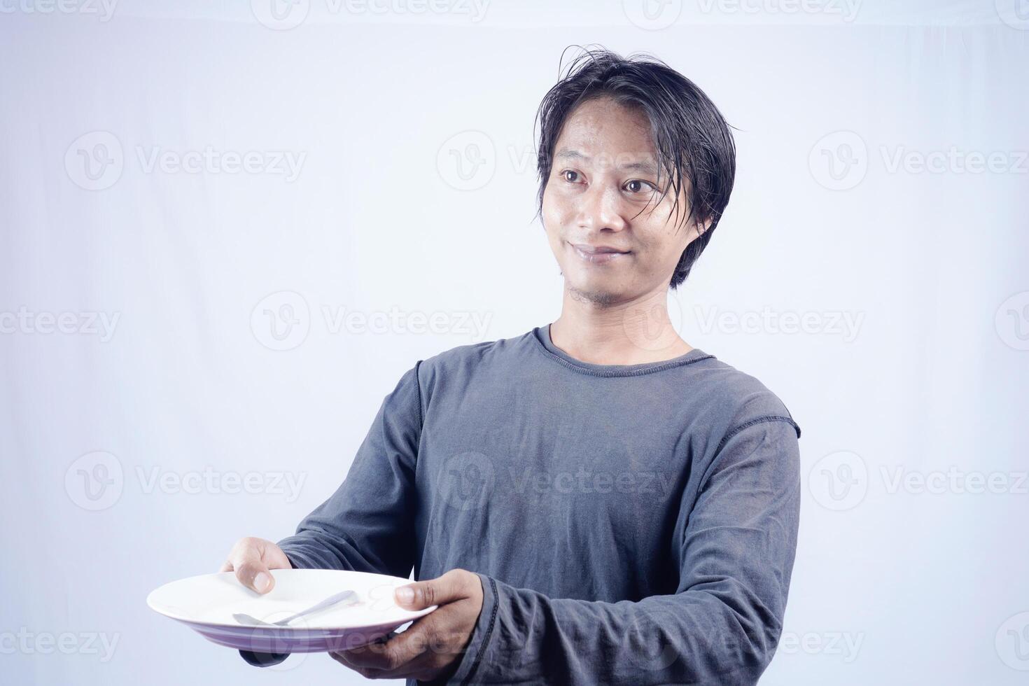 schließen oben Aussicht von gut aussehend asiatisch Mann halten Teller mit glücklich Ausdruck, zeigen Das das Essen ist köstlich auf isoliert Weiß Hintergrund zum Werbung. foto