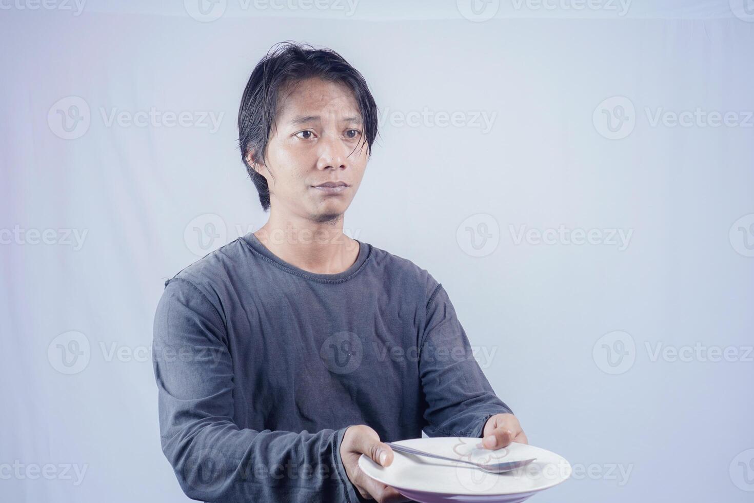 Porträt von asiatisch Männer Wer sind hungrig halten leeren Platten zu Fragen zu Essen mit ein Weiß Hintergrund Das ist isoliert zum das Fotokopie Raum auf Es. Speisekarte Dichter Konzept. foto