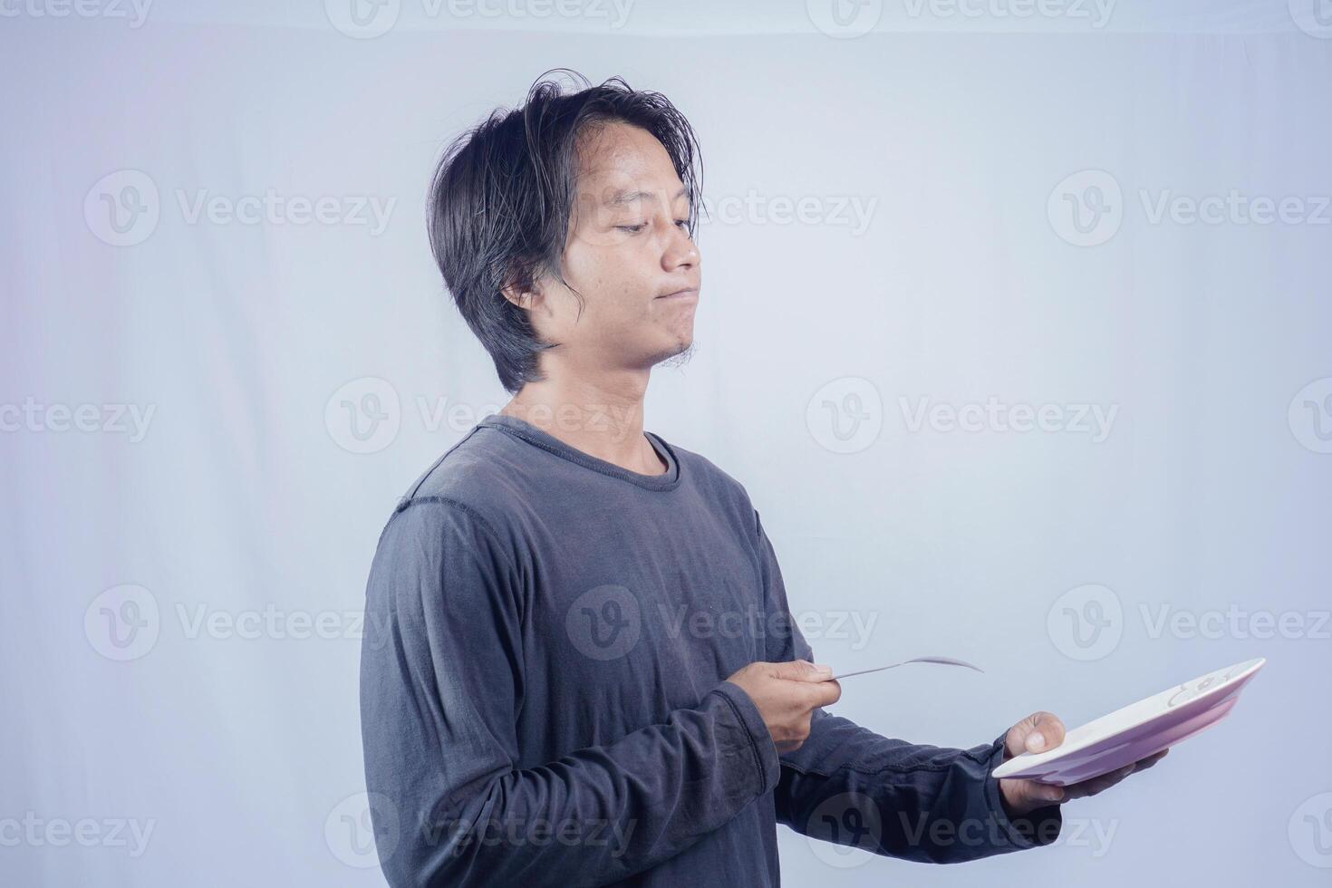 asiatisch Mann zeigen gegenüber leeren Teller mit glücklich Ausdruck isoliert Weiß Hintergrund zum Kaffee Foto Raum. Essen Speisekarte Präsentation Konzept.