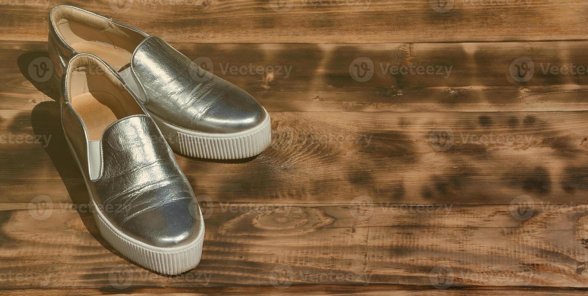 Originale glänzende Schuhe im Disco-Stil liegen auf einer Vintage-Holzoberfläche aus frittierten braunen Brettern. modische Kleidung Retro-Accessoire für Discos und Partys im Stil der Achtziger foto