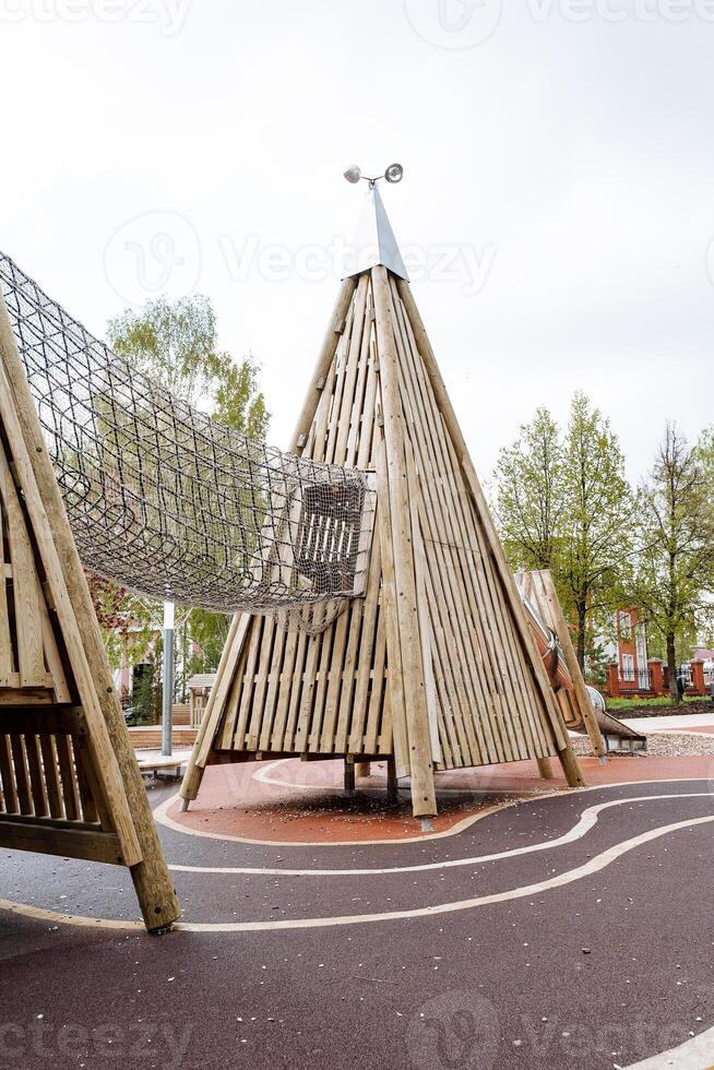 hölzern Pyramide, Gittergewebe Passage zum Kinder, Klettern ein gleiten, ein Erholung Park zum Kinder, ein Gummi Glasur von Asphalt. foto