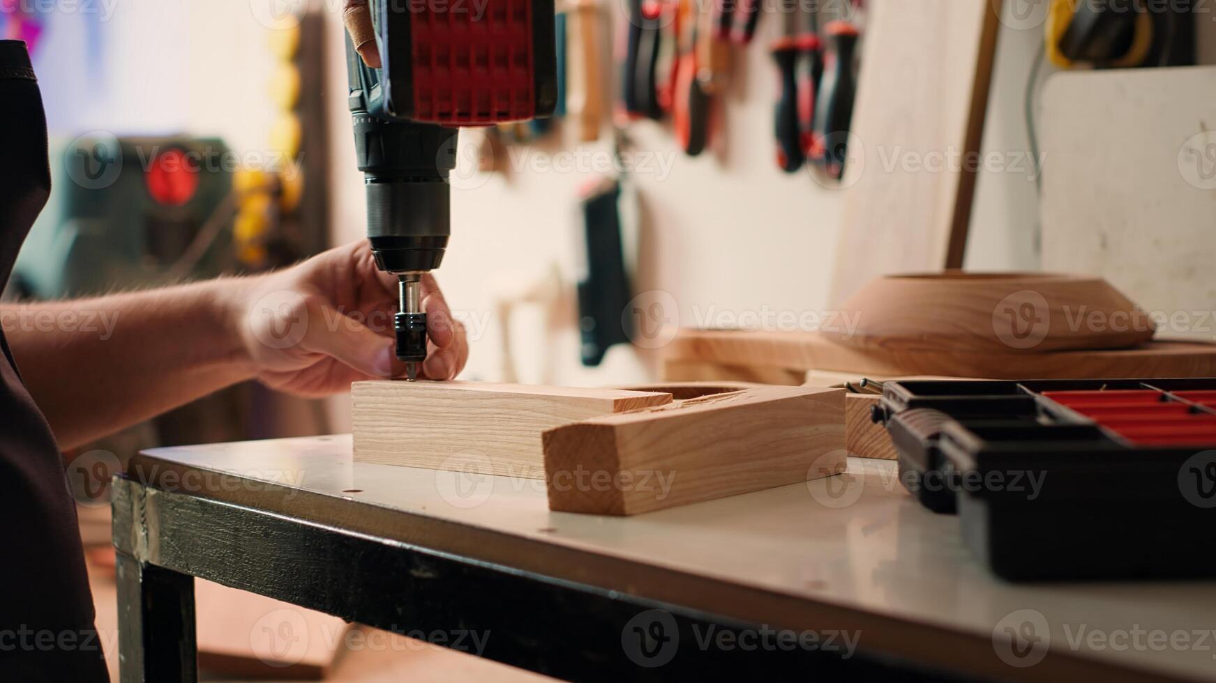 Handwerker Ändern Leistung bohren Kopf in geeignet einer zum Aufgabe voraus, Herstellung Löcher in Holz Block. Hersteller im Versammlung Geschäft Picks Schraube von Werkzeug Box zu verwenden zum in Auftrag arbeiten, Kamera ein foto