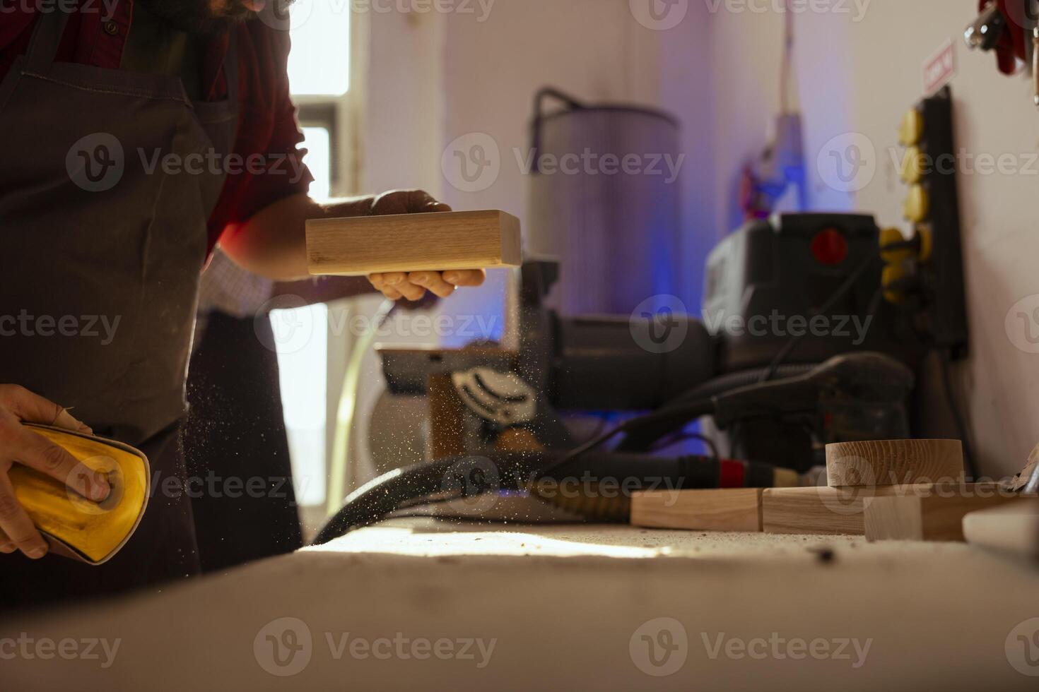 Mann im Versammlung Geschäft mit Sandpapier zum Schleifen hölzern Oberfläche Vor Gemälde Es, gewährleisten angemessen beenden. Zimmermann mit Schleifmittel Schwamm zu Fix Oberfläche Schäden litt durch Holz foto