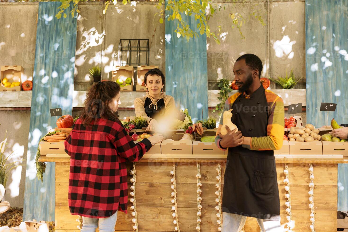 schwarz männlich Farmer zeigen natürlich organisch saisonal produzieren zu Kunde beim grüner Markt Kiosk. Gruppe von Anbieter und Kunden beim Ernte Messe Festival, Surfen frisch geerntet Früchte und Gemüse. foto