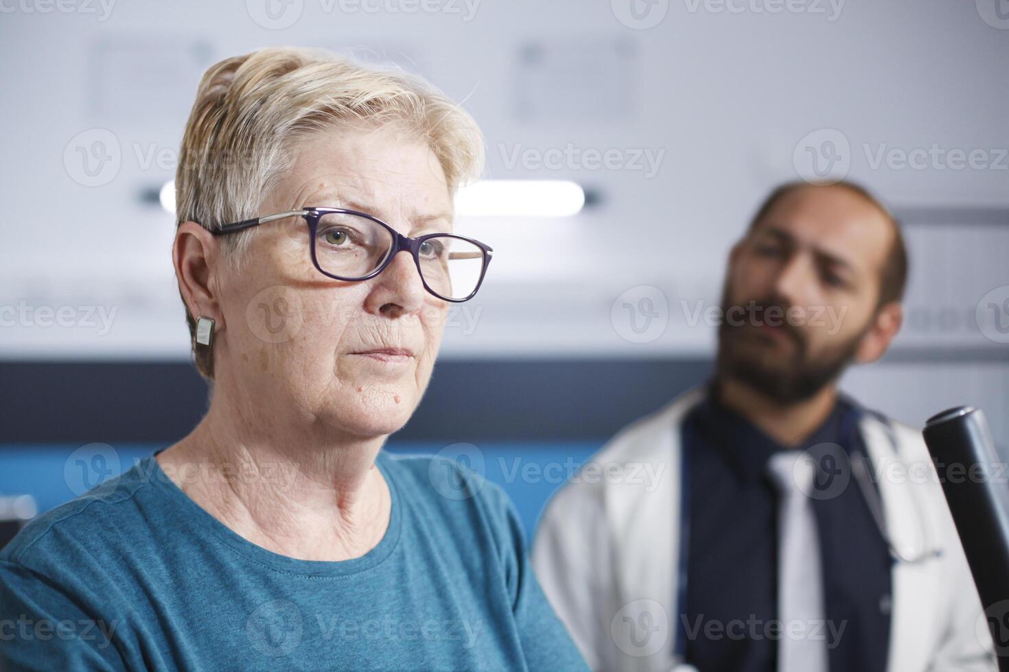 Nahansicht von ein Alten geduldig Ausbildung mit Sport Ausrüstung und Rehabilitation Gang. Porträt von alt Frau mit Brille unterziehen Physiotherapie mit Fachmann männlich Arzt. foto