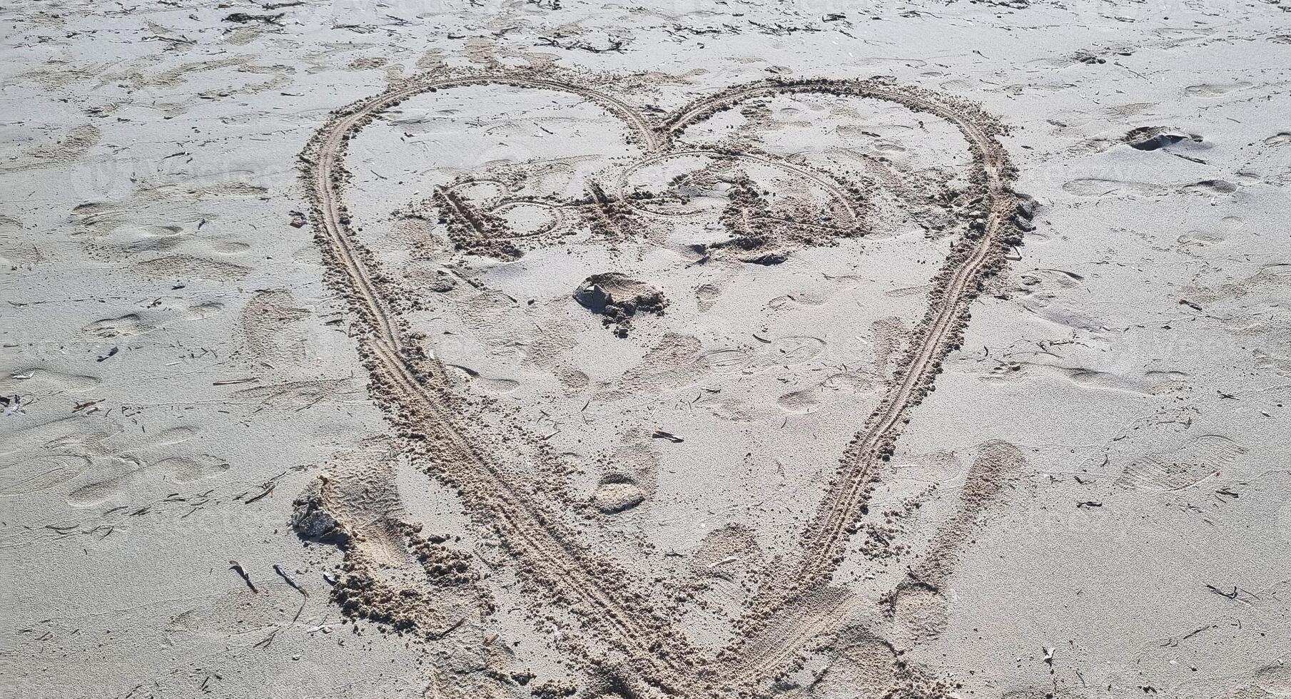 Herz gestalten gezeichnet im das Sand von das Strand. Liebe foto