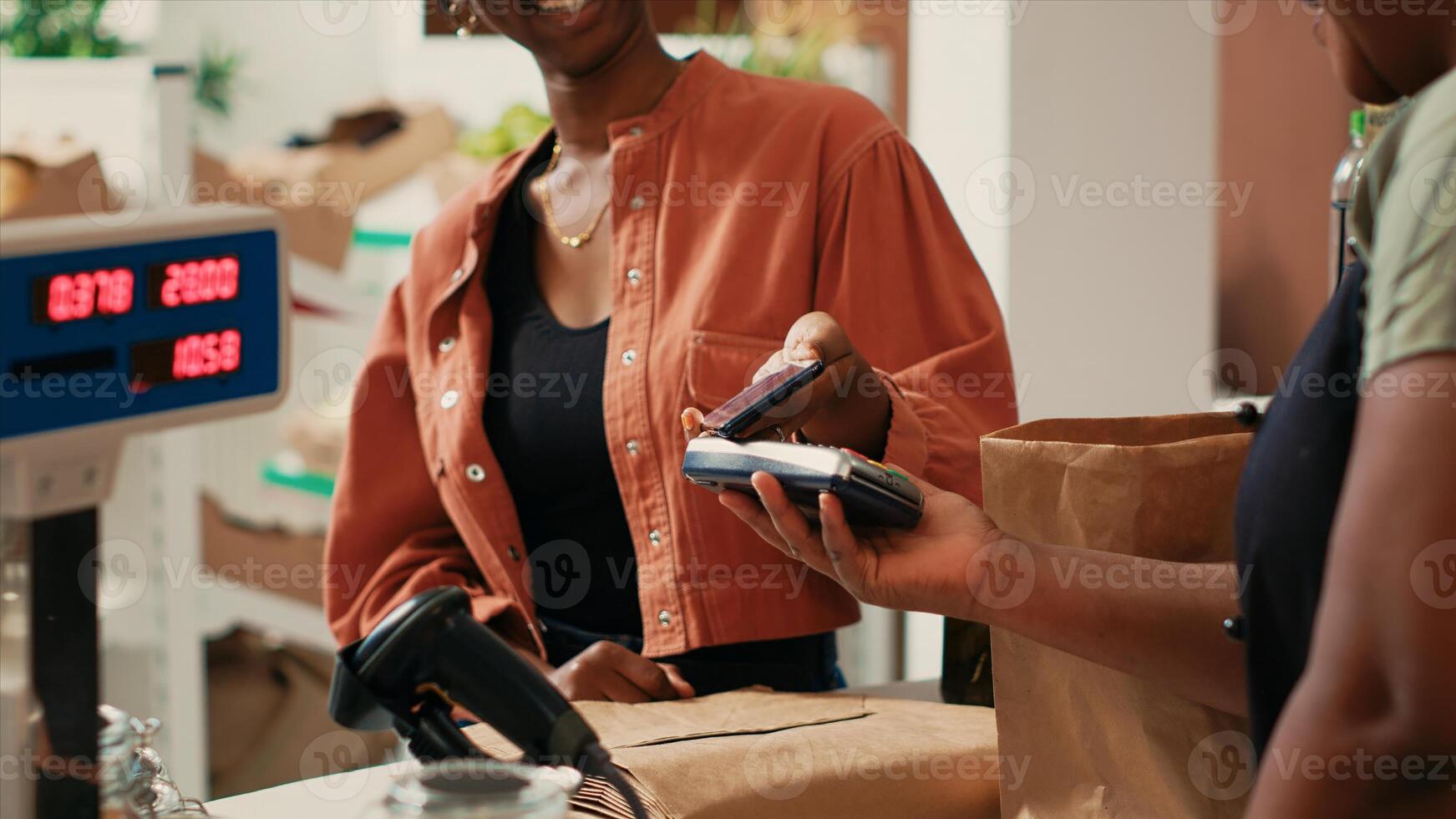 Frau mit Handy, Mobiltelefon nfc Zahlung zu Zahlen zum bio produzieren von lokal Bauernhof, unterstützen nachhaltig Lebensstil und klein Geschäft. afrikanisch amerikanisch Händler und Käufer chatten beim Kasse registrieren. foto