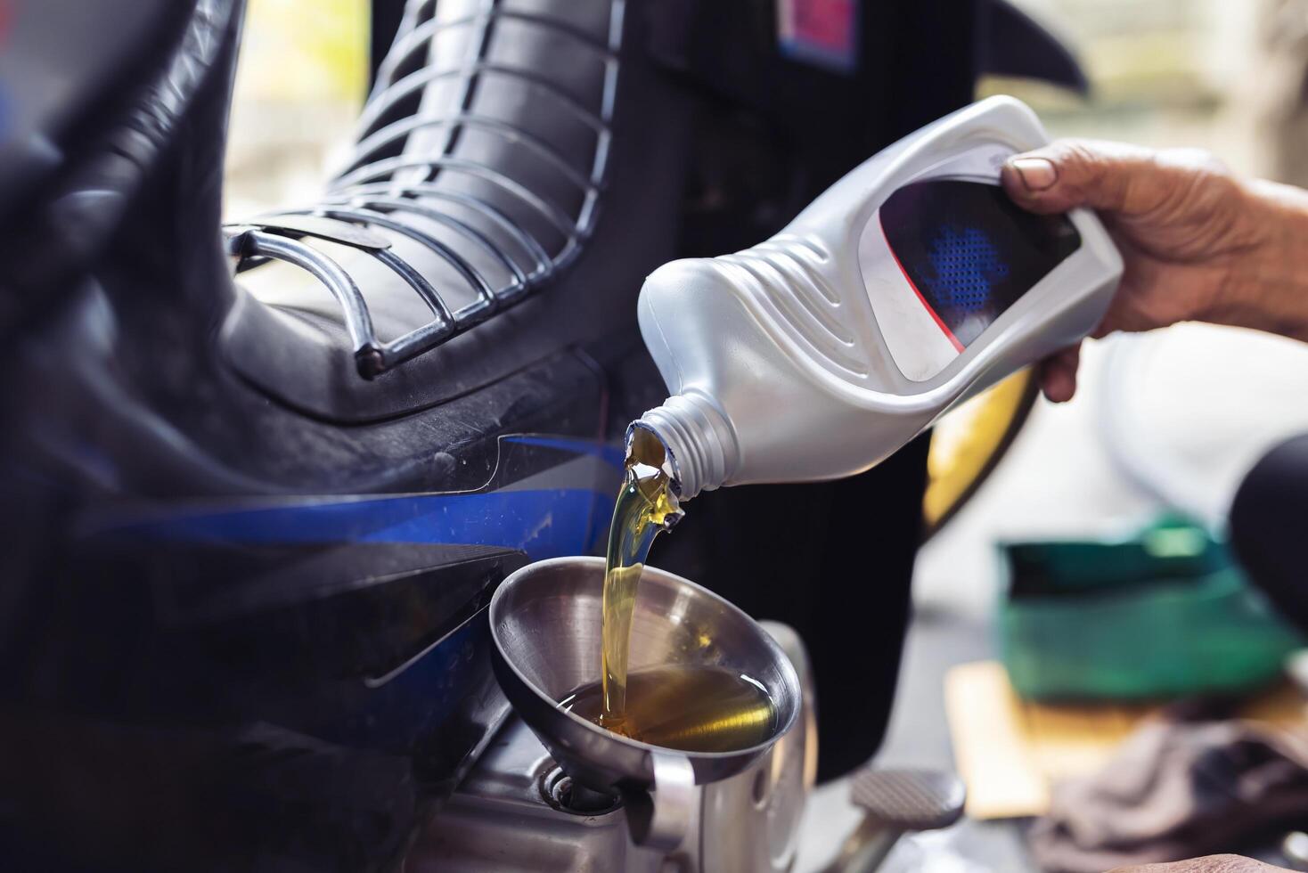 Mechaniker ist ersetzen ein Neu Flasche von Schmiermittel zum ein Motorrad. foto