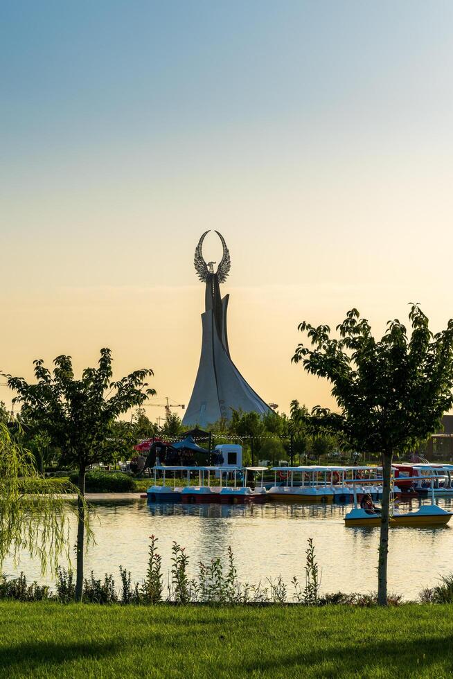 Usbekistan, Taschkent - - September 15, 2023 Monument von Unabhängigkeit im das bilden von ein Stele mit ein Humo Vogel auf ein Dämmerung mit dramatisch Klötze im das Neu Usbekistan Park. foto