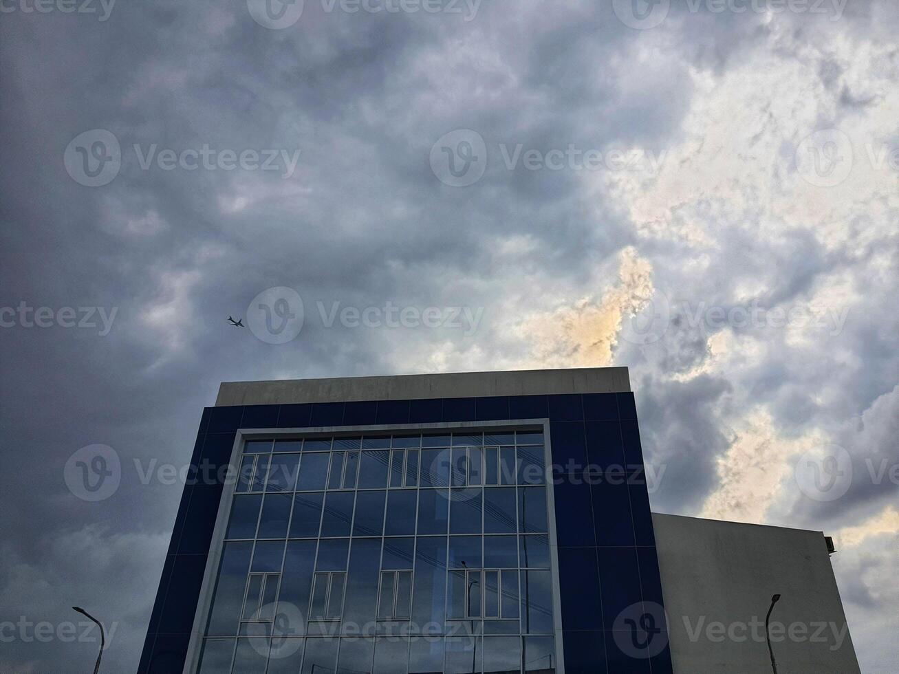 ein Büro Gebäude mit Blau Wände und ein Fassade gemacht von Glas Das spiegelt das Wolken und Himmel foto