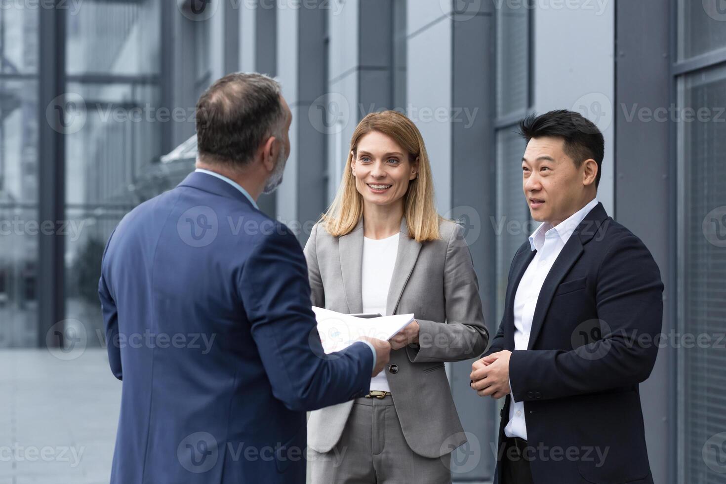 International Geschäft Mannschaft Treffen reifen Mann, kaukasisch Frau, asiatisch Mitarbeiter kommunizieren . Gruppe von Unternehmer im formal Anzüge diskutieren ein Projekt dokumentieren in der Nähe von Büro Center auf Straße foto